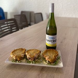 Plato de vieiras gratinadas y botella de vino albariño